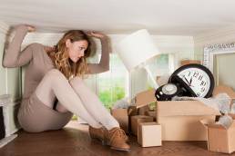 Young woman with box of objects in small room