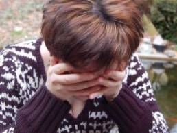 woman looking stressed with her head in her hands featured