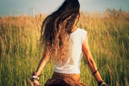 woman walking through a field at sunset featured