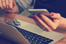 Lady working from home and holding an Iphone in her left hand