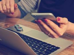 Lady working from home and holding an Iphone in her left hand
