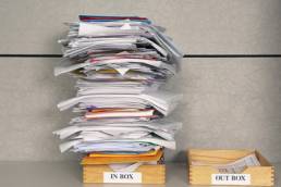 Stacks of papers in two seperate boxes labelled Inbox and Outbox