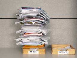 Stacks of papers in two seperate boxes labelled Inbox and Outbox