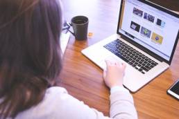 A woman facing away from the camera and using her laptop