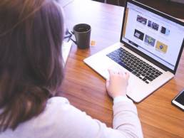 A woman facing away from the camera and using her laptop
