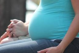 A pregnant woman sitting down and holding hands
