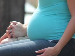 A pregnant woman sitting down and holding hands
