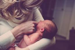 Mothers in the workplace - Woman in a cream cardigan holding her baby