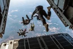 A group of people jumping out of the back of the plane to go skydiving