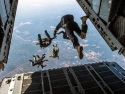 A group of people jumping out of the back of the plane to go skydiving