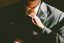Man straightening tie when wearing a suit
