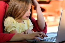 children learning to use computer with parent featured