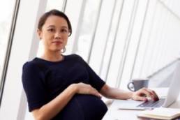 pregnant woman at her desk featured