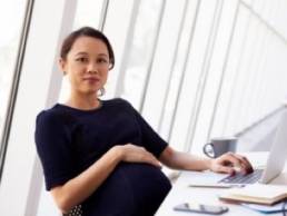 pregnant woman at her desk featured
