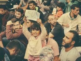 refugees huddled together at train station featured