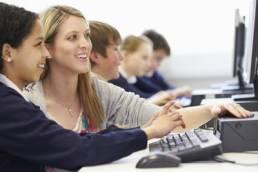teacher guiding female student in IT lesson featured