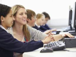 teacher guiding female student in IT lesson featured