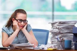 Woman looking miserably at her pile of work