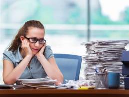 Woman looking miserably at her pile of work