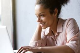 Young, smiling woman smiling whilst on her laptop