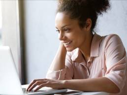 Young, smiling woman smiling whilst on her laptop