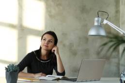 woman thinking at her desk with computer