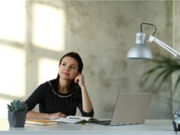 woman thinking at her desk with computer