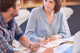 confident woman mentoring male colleague featured