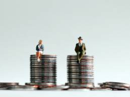 man and woman sitting on pile of coins, Equal Pay Day