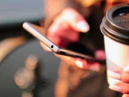 Woman holding coffee and phone, emails featured