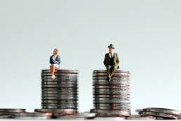 man and woman sitting on coins, equality