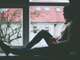 young woman looking out of window, sad, coronavirus, stress