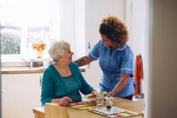 Care worker giving an old lady her dinner in her home