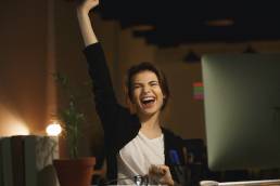 Picture of yawning young woman designer sitting in office at night using computer.
