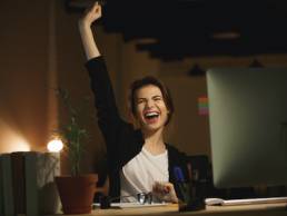 Picture of yawning young woman designer sitting in office at night using computer.