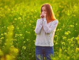 woman with hayfever standing in a field of flowers, allergies