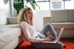 young woman working from home, using her laptop on the floor