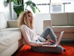 young woman working from home, using her laptop on the floor