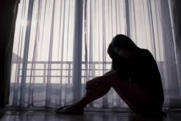 Sad woman sitting alone near window, human trafficking