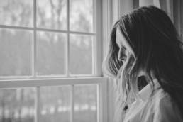 sad woman looking out of the window, grief, bereavement