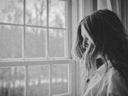 sad woman looking out of the window, grief, bereavement