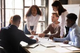 Serious international diverse business team people and african female leader boss discuss financial result review paperwork, being an ally