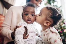 Little Girl Kissing her Baby Cousin, Refuge Christmas campaign