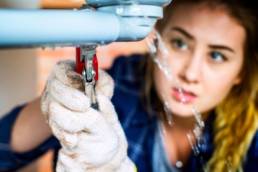 Woman fixing kitchen sink, Female Plumber, Women in plumbing featured