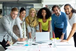 Front view of diverse business people looking at camera while working together at conference room in a modern office