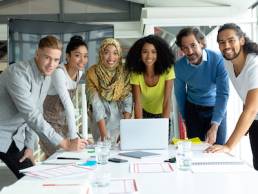 Front view of diverse business people looking at camera while working together at conference room in a modern office