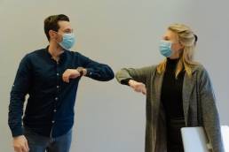 co-workers greeting each other during COVID-19, re-onboarding team members