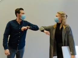 co-workers greeting each other during COVID-19, re-onboarding team members