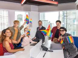 Business office workers from different ethnicities express support for self determination in LGBT. Business people showing LGBT flags in an office. Business people support Gender Equality