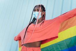 young gay black woman holding pride banner, LGBTQ